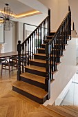Restored wooden staircase in open-plan living area with classic chairs and exotic-wood parquet flooring