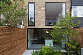 Modern erneuerte Fassade eines historischen Reihenhauses mit Vollverglasung und Garten zwischen Sichtschutzwänden aus Holz