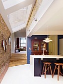 Offene Küche mit weißem Fliesenboden und modernem Oberlichtband zwischen Ziegelwänden, Blick in Wohnbereich