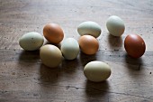 Various different coloured hens' eggs on a wooden surface