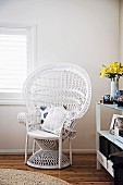 Asian rattan peacock chair painted white in the corner of the room