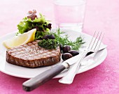 Grilled tuna steak with dill pesto, olives and a side salad