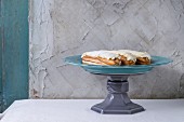 Homemade eclairs with white buttercream on retro turquoise cake stand