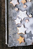 Glazed star-shaped Christmas biscuits with icing sugar on a baking tray