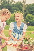 Little girls wearing dirndls and wreaths in their hair at a table outside
