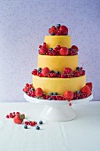 A three-tier, yellow fondant cake decorated with fresh berries