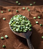 Green dried split peas on a wooden spoon