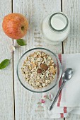Gesundes Frühstück: Müsli mit Nüssen, Apfel & Milch auf Holztisch