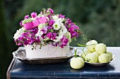 Romantische Blumengesteck mit Äpfeln und Silberschale auf Vintage Koffer im Freien