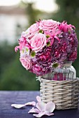 Romantischer Brautstrauß mit rosafarbenen Rosen in Glasvase und Korbübertöpfchen
