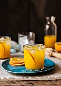 A glass of orange juice with fruit slices of ice cubes