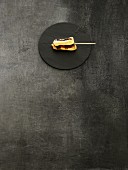A kushi skewer on a black stone platter