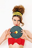 Young woman holding target with dart stuck in tomato