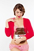 Young woman wearing underwear and cardigan with large jar of Nutella