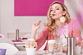 Junge Frau sitzt an Tisch eines Cafes & trinkt Latte Macchiato