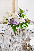 Spring dining table festively set with vase of lilac