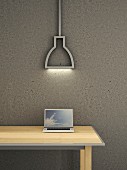 Laptop auf Holztisch vor grauer Betonwand darüber moderne Neonleuchte