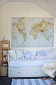 Pale blue cushions on child's bed with integrated drawers below world map hung on gable-end wall of attic room