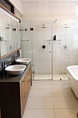 Designerbad mit zwei Waschbecken, Spiegelhängeschrank und zwei Regenduschen hinter Glasabtrennung