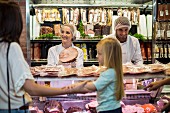Customers and sales staff at a meat counter in a supermarket