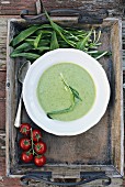 Wild garlic soup on a wooden tray with wild garlic leaves and tomatoes