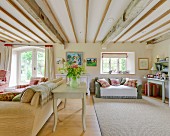 Ländliches Wohnzimmer mit Holzbalkendecke, Polstermöbeln und elegantem Flair