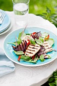 Grilled haloumi and red onions on a vegetable and lettuce salad