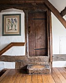 Antique wooden steps leading to rustic, restored wooden door in attic