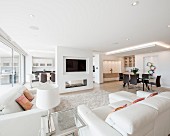 Luxuriöser offener Wohnraum, mit weißen Sofas und modernem Essplatz