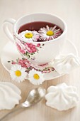 Daisies floating in tea in floral teacup