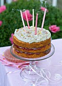 A birthday cake with blown out candles on a table outside
