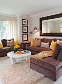 Corner sofa with brown cover and white coffee table on Berber rug in traditional living room