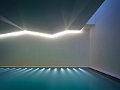 Indoor swimming pool with submerged lights and indirect ceiling lighting in angular ceiling
