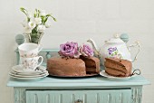 Chocolate cake with coffee crockery on a mint coloured sideboard