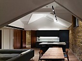 Offener Wohnraum in minimalistischem Designerstil mit indirekter Beleuchtung im Dachgeschoss eines ehemaligen Industriegebäudes