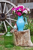 Blue enamel jug of Sweet William on tree stump