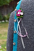 Buttonhole of Sweet William and ribbons pinned to traditional German cardigan
