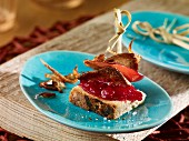 Rabbit liver skewers with onion rings, apple slices and lingonberry compote on a slice of bread