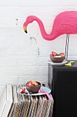 Mit Luftballons gestaltete Schokoladenschalen mit Früchten als essbares Partygeschirr und dekorative Flamingofigur auf Lautsprecherbox