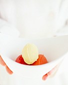 Hands holding a bowl of vanilla ice cream, blood orange sorbet and strawberry sorbet
