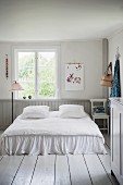 Romantisches Doppelbett auf weißem Dielenboden in ländlichem Schlafzimmer mit nostalgischem Flair
