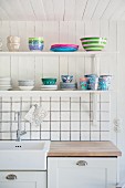 Crockery on bracket shelves above kitchen counter and white-tiled splashback