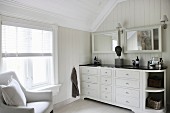 Washstand with twin sinks and armchair in elegant attic bathroom