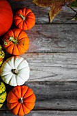 Bright pumpkins and autumn leaves on rustic wooden surface