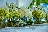 Verschiedene Blumensträusse in Glasvase auf Hochzeitstisch