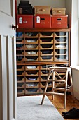 Haberdashery cabinet used as chest of drawers, step ladder and red storage boxes in dressing room