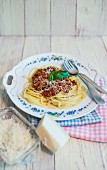 Spaghetti Bolognese and grated Grana Padano cheese on a porcelain plate