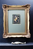 Antique picture in gilt frame above sculpture of supine figure