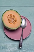 Half a cantaloupe melon on a pink porcelain plate
