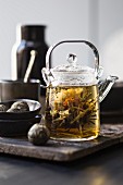 Weisser Tee in Glasteekanne mit Teeblume